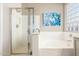 Sunlit bathroom features a seamless glass shower, soaking tub, and privacy glass block window at 9623 S 25Th Ln, Phoenix, AZ 85041