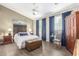 Bright main bedroom with wood-look floors, ceiling fan, chest, and decorative headboard and drapes at 9623 S 25Th Ln, Phoenix, AZ 85041
