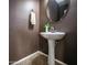 Elegant powder room with pedestal sink, decorative mirror, and textured walls, creating a sophisticated and functional space at 10136 E Isleta Ave, Mesa, AZ 85209