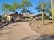 Manicured home exterior with a circular driveway, mature trees, desert landscaping, and a welcoming facade at 10523 E Sleepy Hollow Trl, Gold Canyon, AZ 85118