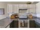 Kitchen with stainless steel appliances, white cabinetry, granite countertops, and subway tile backsplash at 10702 W Orangewood Ave, Glendale, AZ 85307