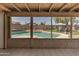 A view of the pool from an enclosed patio area, showcasing the backyard amenities and outdoor living space at 10702 W Orangewood Ave, Glendale, AZ 85307