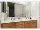 Bright bathroom featuring a dual sink vanity with wood cabinets, a large mirror, and neutral décor at 11206 W Coronado Rd, Avondale, AZ 85392