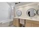 Bright bathroom with dual sinks, a vanity area, a soaking tub, and excellent lighting at 11550 W Mule Deer Ct, Surprise, AZ 85378