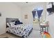 Bright bedroom with a fun patterned bedspread, a desk, and a sunny window at 11550 W Mule Deer Ct, Surprise, AZ 85378