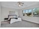 Cozy bedroom with soft carpet, tray ceiling, a ceiling fan, and ample natural light from the large window at 11717 W Red Hawk Dr, Peoria, AZ 85383