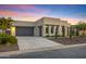 Contemporary desert home featuring a gray garage door and desert landscaping at dusk at 11717 W Red Hawk Dr, Peoria, AZ 85383