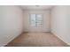An empty carpeted bedroom with a window provides a blank canvas for personalization and comfortable living at 14936 W Maui Ln, Surprise, AZ 85379