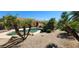 Lush backyard featuring a swimming pool, mature landscaping, and desert flora at 15728 W Verde Ln, Goodyear, AZ 85395