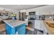 Bright kitchen with stainless steel appliances, white cabinets, a blue island, and view into the living room at 18035 N 29Th Dr, Phoenix, AZ 85053