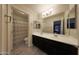 Bathroom featuring a double vanity, spacious mirror, decorative shower curtain, and wood-look vinyl flooring at 20545 W Terrace Ln, Buckeye, AZ 85396