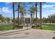 Scenic view of a community park with a central fountain, palm trees, and a building in the background at 20545 W Terrace Ln, Buckeye, AZ 85396