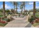 Community park featuring a water fountain, palm trees, flowers, and buildings in the background at 20545 W Terrace Ln, Buckeye, AZ 85396
