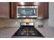 Kitchen featuring a stainless steel gas range and microwave with sleek countertops and tiled backsplash at 20545 W Terrace Ln, Buckeye, AZ 85396