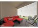 Cozy covered patio showcasing a red sofa with throw pillows, turf, and seating, ideal for outdoor relaxation at 20545 W Terrace Ln, Buckeye, AZ 85396