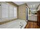 Inviting bathroom featuring a soaking tub, shuttered window, and wood floors at 211 W Kaler Dr, Phoenix, AZ 85021