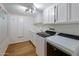 Functional laundry room with laminate floors, white cabinetry, sink and modern appliances at 211 W Kaler Dr, Phoenix, AZ 85021