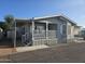 Charming home exterior with covered porch, white railings, and well-maintained landscaping under a clear blue sky at 2121 N Center St # 131, Mesa, AZ 85201