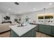 Open kitchen with an island, sage cabinets, white quartz countertops, and stainless steel appliances, flowing into the living area at 2753 E Aster Dr, Phoenix, AZ 85032