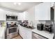 Galley kitchen with stainless appliances, white cabinetry, and marble countertops at 3646 N 67Th Ave # 29, Phoenix, AZ 85033