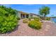 Backyard boasts a peaceful lake, colorful flowering plants, and a covered patio for outdoor enjoyment at 42485 W Abbey Rd, Maricopa, AZ 85138