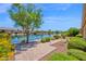 Serene backyard featuring a stone patio, lush landscaping, and a picturesque lake view on a sunny day at 42485 W Abbey Rd, Maricopa, AZ 85138