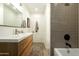 Modern bathroom featuring a wood vanity, stylish lighting, and subway tile in the shower at 547 W Orangewood Ave, Phoenix, AZ 85021