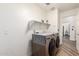 Bright laundry room with a front-loading washer and dryer set, overhead shelving, and durable flooring at 6232 N 88Th Ave, Glendale, AZ 85305