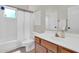 Well-lit bathroom with a clean vanity, wood cabinets, and shower with a white curtain at 7532 E Sierra Morena Cir, Mesa, AZ 85207