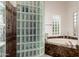 Bathroom boasting a glass block shower, soaking tub, and natural lighting at 8324 E Cactus Wren Rd, Scottsdale, AZ 85250