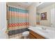 Well-lit bathroom featuring a colorful shower curtain, vanity, and a framed mirror at 8621 W Morten Ave, Glendale, AZ 85305