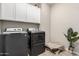Modern laundry room with front-load washer and dryer and storage cabinets at 8735 N 185Th Ave, Waddell, AZ 85355