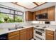 Functional kitchen featuring wood cabinets, light countertops, white appliances, and a view from the window at 10235 N 31St St # 2, Phoenix, AZ 85028