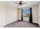 Cozy carpeted bedroom featuring a ceiling fan and a large window with dark curtains at 10617 W Ross Ave, Peoria, AZ 85382