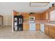 Well-lit kitchen featuring wood cabinets, black refrigerator, white appliances, and tile flooring at 10617 W Ross Ave, Peoria, AZ 85382