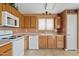 Functional kitchen featuring wood cabinets, white appliances, and neutral countertops and tile flooring at 10617 W Ross Ave, Peoria, AZ 85382
