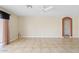 Open living room with tile floors, ceiling fan, sliding door with curtains, and arched entryways at 10617 W Ross Ave, Peoria, AZ 85382