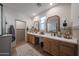 Bathroom featuring dual vanities, quartz countertop, and a glass-enclosed shower with tile surround at 10964 W Garfield St, Avondale, AZ 85323
