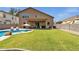 An expansive backyard features a large grassy area, pool, covered patio, and outdoor seating, perfect for relaxing and entertaining at 1130 E Harvest Rd, San Tan Valley, AZ 85140