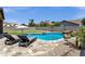 An inviting backyard features a sparkling pool, lush lawn, lounge chairs, and desert landscaping, perfect for outdoor enjoyment at 1130 E Harvest Rd, San Tan Valley, AZ 85140