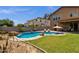 An inviting backyard pool is surrounded by desert landscaping, rocks, mature palm trees, and lounge chairs, creating a private oasis at 1130 E Harvest Rd, San Tan Valley, AZ 85140