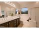 Elegant bathroom with double sinks, soaking tub, glass-enclosed shower, and decorative accents at 13145 W Whisper Rock Trl, Peoria, AZ 85383
