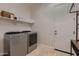 Well-equipped laundry room with modern washer and dryer, storage shelf, and tile flooring at 13145 W Whisper Rock Trl, Peoria, AZ 85383