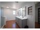 Bathroom showcasing a double sink vanity, framed mirrors, wood-look tile flooring, and a separate shower at 13601 W Hearn Rd, Surprise, AZ 85379