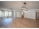 Open-concept living area featuring wood-look floors, a ceiling fan, and an elegant pendant light at 13601 W Hearn Rd, Surprise, AZ 85379