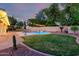 Backyard with green grass, beautiful plants, landscape lighting and in-ground pool at 14687 W Amelia Ave, Goodyear, AZ 85395