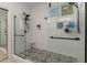 Newly remodeled shower showcasing sleek glass doors, stylish black-and-white tile floors, and white subway tile surround at 14687 W Amelia Ave, Goodyear, AZ 85395