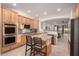 Open kitchen with natural wood cabinets, granite island with seating, stainless steel appliances, and tile flooring at 14687 W Amelia Ave, Goodyear, AZ 85395