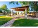 Outdoor covered patio featuring a fireplace, fan, and table with chairs, ideal for entertaining at 14687 W Amelia Ave, Goodyear, AZ 85395