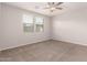 Cozy bedroom with neutral carpet, a ceiling fan, and two windows with blinds at 15078 W Mckinley St, Goodyear, AZ 85338